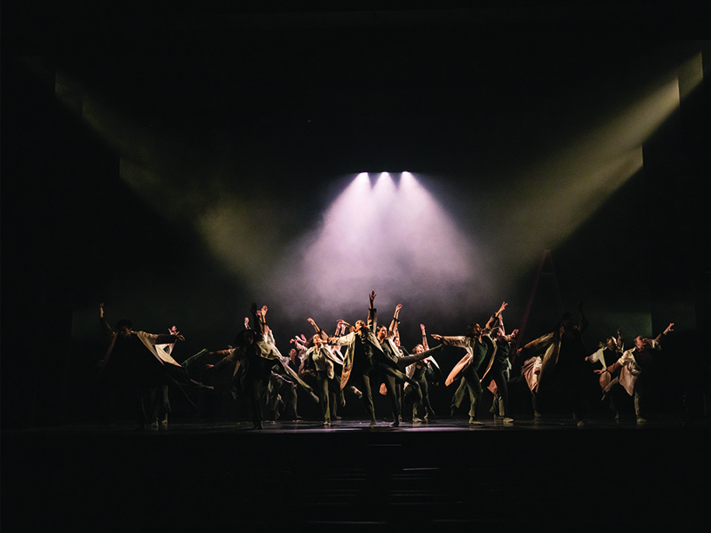 Dance students are pictured with a spotlight overhead during their performance.